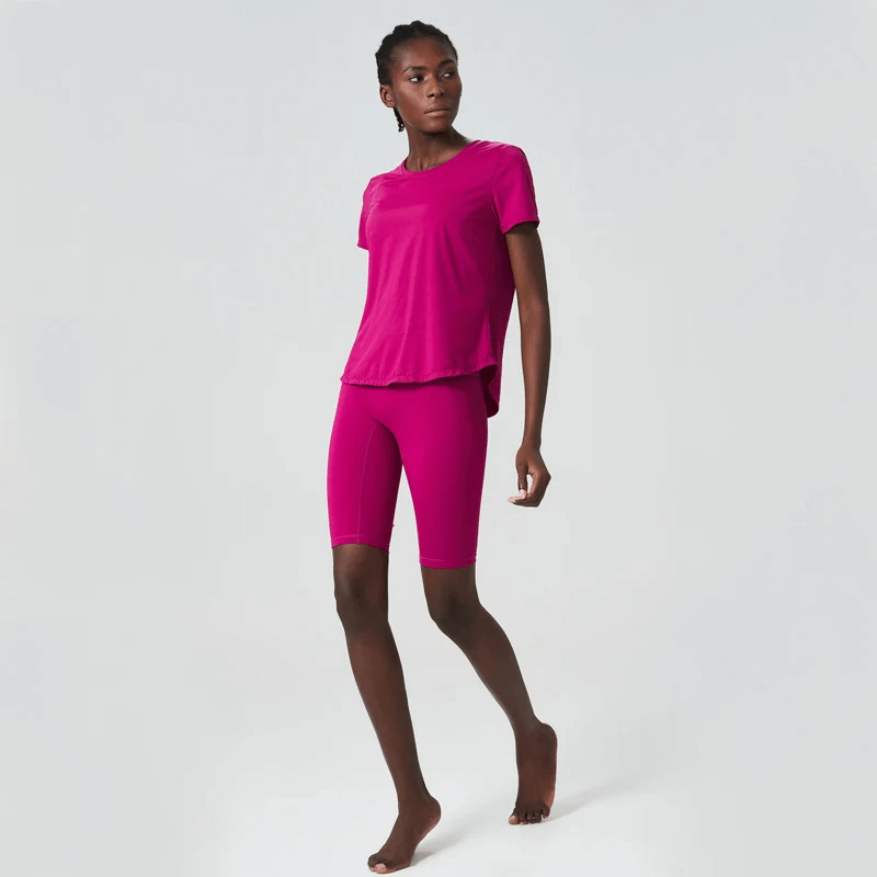 Woman wearing a pink solid color yoga set, showcasing short sleeves and quick-dry features, perfect for gym, running, and yoga sessions.